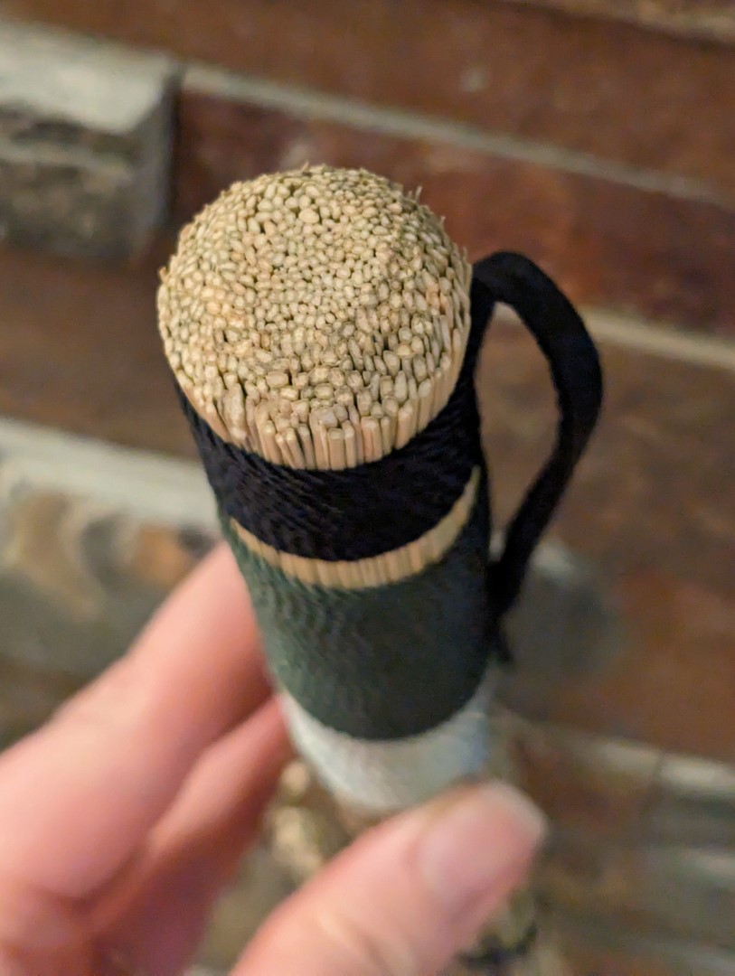 Top of broom handle is carved into a dome shape